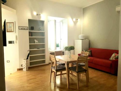 ein Wohnzimmer mit einem Tisch und einem roten Sofa in der Unterkunft St Peter Charming House in Rom