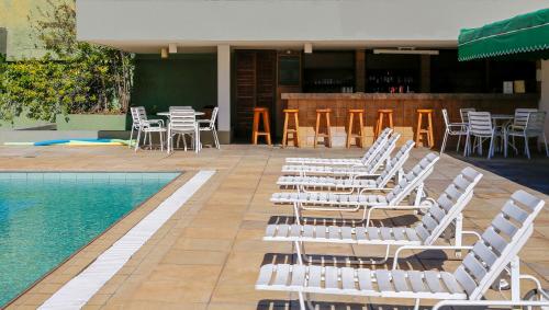 a group of white chairs and a swimming pool at VOA Hotel União in Caxambu