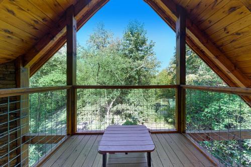 a wooden porch with a bench in front of a large window at Knotty Escape in Gatlinburg