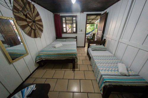 a room with two beds and a mirror on the wall at Pousada Recanto Tropical in Ilha do Mel