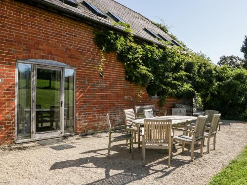 a table and chairs in front of a brick building at Breaches Barn in Rockbourne