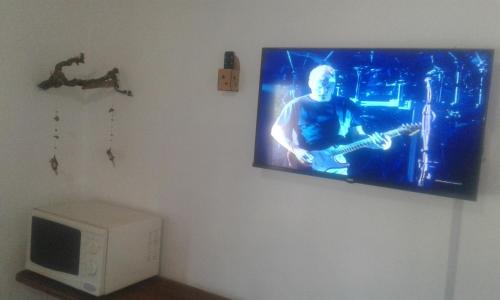 un televisor colgando de una pared con un guitarrista en él en Las Cuatro Estaciones en San Rafael