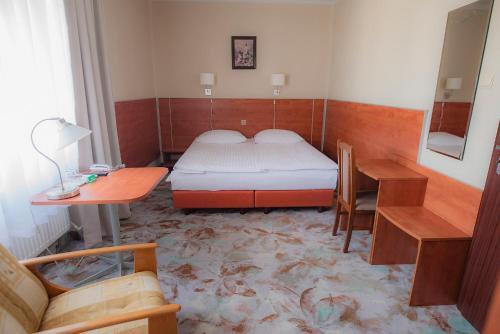 a bedroom with a bed and a desk and a table at Hotel Włókniarz in Pabianice