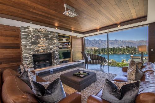 a living room with a stone fireplace and a couch at Lakeview by Sothebys Luxury Rental Homes in Queenstown