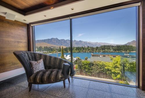 a living room with a chair and a large window at Lakeview by Sothebys Luxury Rental Homes in Queenstown
