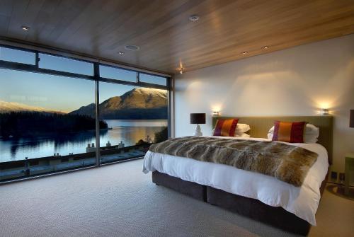 a bedroom with a large bed and a large window at Lakeview by Sothebys Luxury Rental Homes in Queenstown