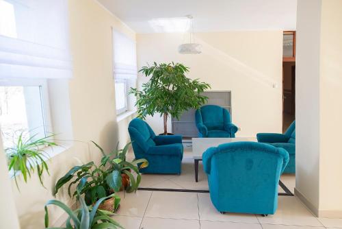 a waiting room with blue chairs and plants at Hotel Włókniarz in Pabianice