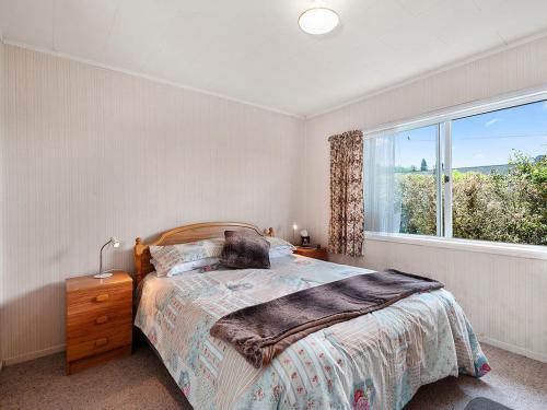 ein Schlafzimmer mit einem Bett und einem großen Fenster in der Unterkunft Central Riverside Retreat - Taupo Holiday Home in Taupo