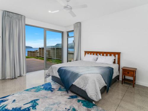 a bedroom with a bed and a large window at Mana Sarovar - Lake Tarawera Home in Lake Tarawera