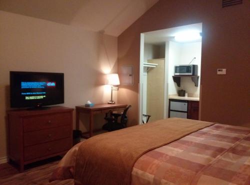 1 dormitorio con 1 cama y TV de pantalla plana en FieldHouse Inn & Conference Center en Kenedy