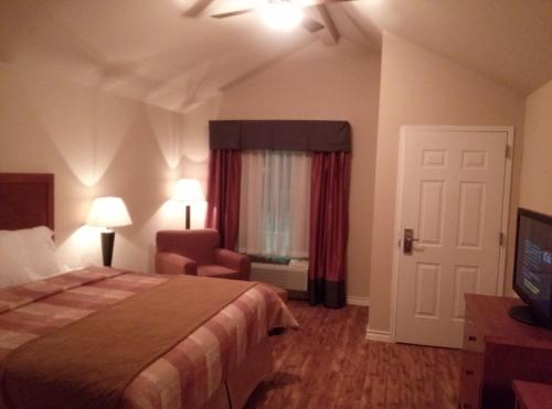 Habitación de hotel con cama, silla y TV en FieldHouse Inn & Conference Center, en Kenedy