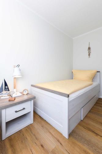 a white bedroom with a bed and a desk at Ferienwohnungen Min Huus in Neuharlingersiel