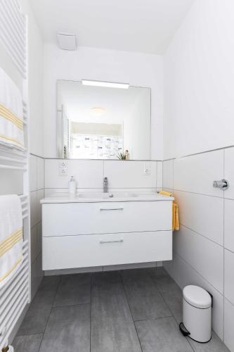 a white bathroom with a sink and a mirror at Ferienwohnungen Min Huus in Neuharlingersiel