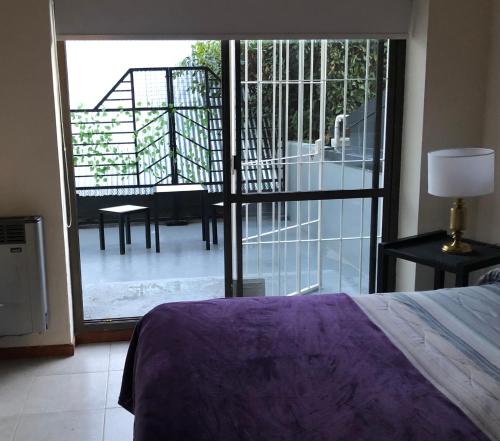 1 dormitorio con cama y vistas a un balcón en el Departamento Céntrico Bariloche con patio en San Carlos de Bariloche