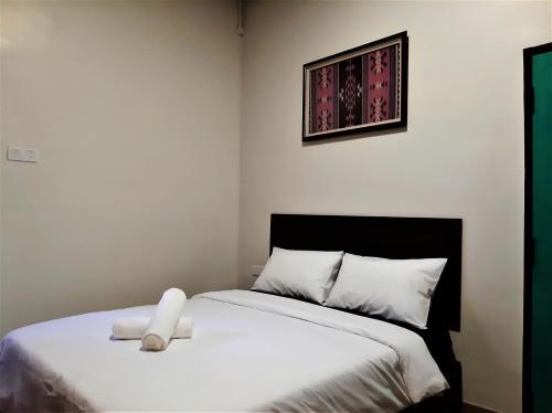 a bedroom with a white bed with a black headboard at Blue Eyes Hotel in Kepala Batas