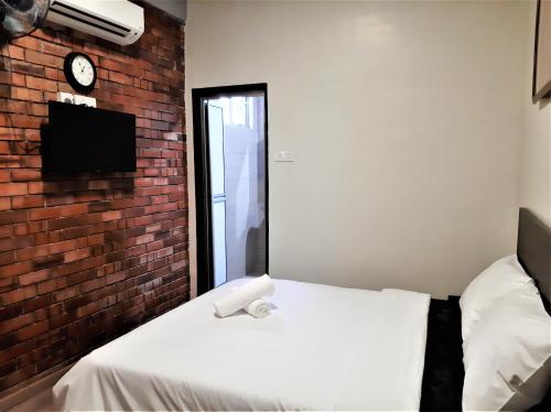 a bedroom with a white bed and a brick wall at Blue Eyes Hotel in Kepala Batas
