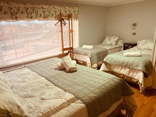 1 dormitorio con 2 camas y ventana en Arte Brisa Hostal Boutique, en Puerto Natales