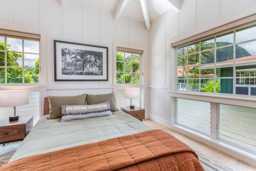 a bedroom with a large bed and two windows at Camp Alealea 2 home in Hanalei