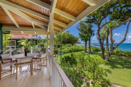 a porch with a table and chairs and the ocean at Camp Alealea 2 home in Hanalei
