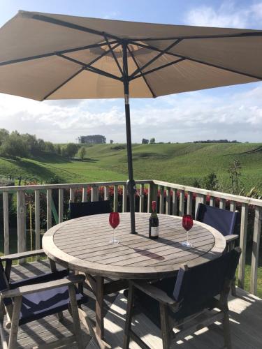 a table with two wine glasses and an umbrella on a deck at Ataahua Homestay in Feilding