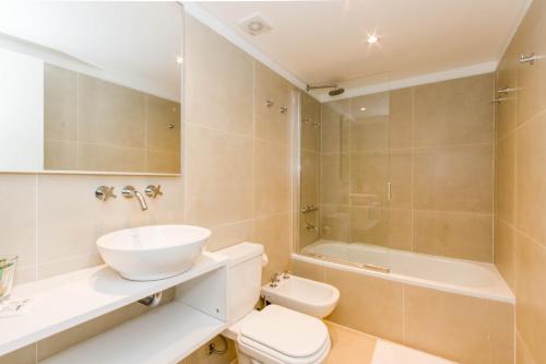 a bathroom with a sink and a toilet and a tub at Austral Departamentos in Ushuaia