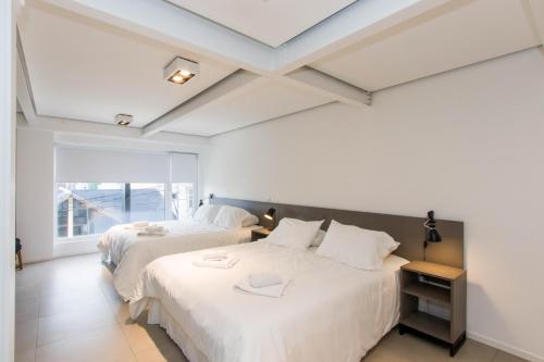 two beds in a room with white walls at Austral Departamentos in Ushuaia