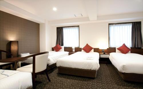 Hotel Sun White في أوساكا: غرفة فندقية بأربعة أسرة وطاولة