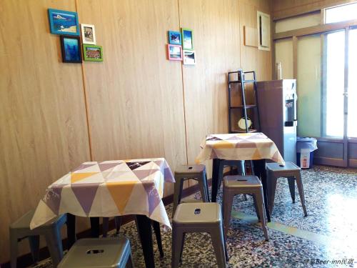 kuchnia z dwoma stołami i stołkami oraz lodówką w obiekcie Beer Inn綠島 w mieście Lü Dao