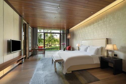 a bedroom with a large white bed and a television at Yanqi Hotel, Managed by Kempinski in Huairou