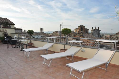 a patio with white chairs and tables on a roof at Hotel Urbano V in Montefiascone