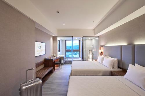a hotel room with two beds and a desk at Grand Bay Resort Hotel in Hengchun