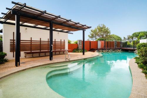 a large swimming pool with a bench and a building at The Sebel Twin Waters in Twin Waters