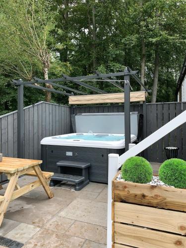 a hot tub in a backyard with a fence at Percy Wood Lodges with Hot Tubs in Swarland
