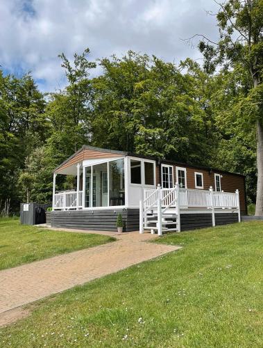 a small house with a porch on a grass field at Percy Wood Lodges with Hot Tubs in Swarland