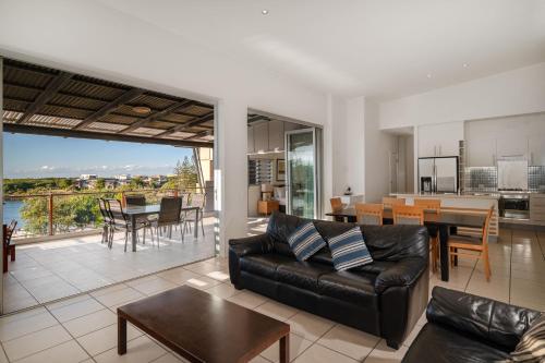 a living room with a leather couch and a dining room at The Sebel Twin Waters in Twin Waters