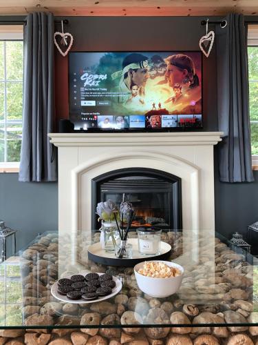 a living room with a fireplace with a tv above it at Percy Wood Lodges with Hot Tubs in Swarland