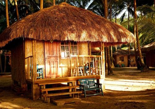 une petite cabane avec des chaises et un toit de paille dans l'établissement Arkadia Beach Resort by RedDoorz, à Sabang