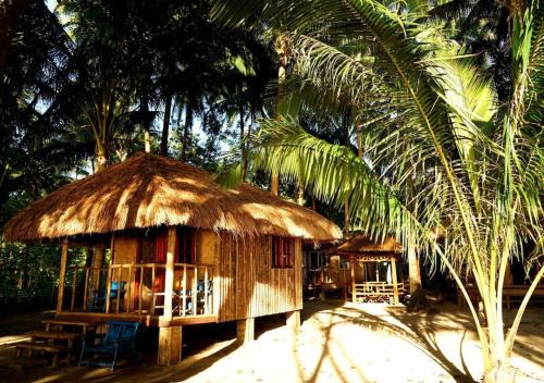 une petite cabane avec un toit de paille et un palmier dans l'établissement Arkadia Beach Resort by RedDoorz, à Sabang