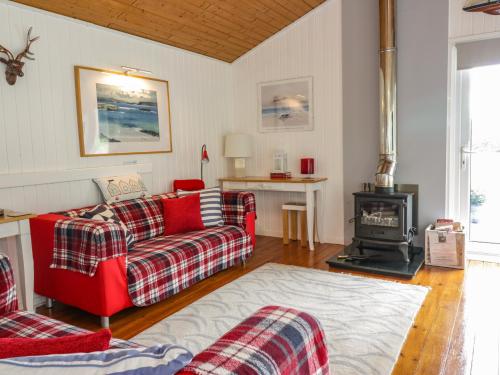 a living room with a red couch and a stove at Meadow Lodge in Coldingham