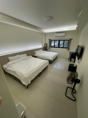 a bedroom with two beds and a television in it at Home Rest B&B in Lijia