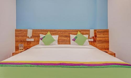 a bedroom with a white bed with green and purple pillows at Itsy Hotels Classio Richmond in Bengaluru