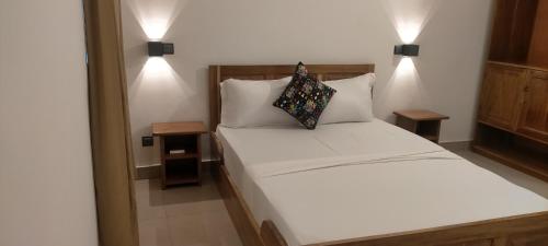 a bedroom with a white bed with two pillows at AZURIA HOTEL in Lomé