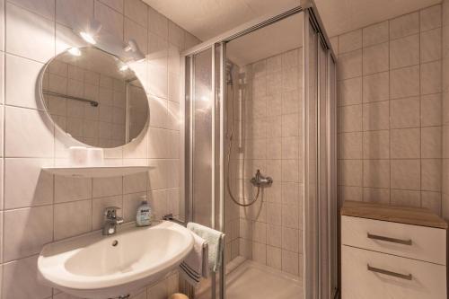 a bathroom with a sink and a shower with a mirror at Ferienwohnung Grauer in Moos