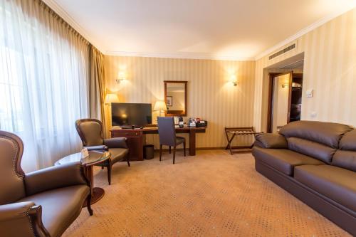 a living room with a couch and a desk with a television at Ramada Hotel & Suites by Wyndham Bucharest North in Bucharest