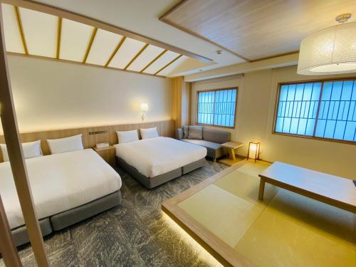 um quarto com duas camas, uma mesa e janelas em IAM HOTEL em Osaka
