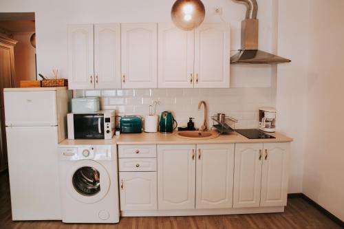 uma cozinha com armários brancos e uma máquina de lavar roupa em SEA 59 em Mamaia
