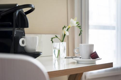 a table with two cups and a vase with flowers at Hotel Max in Paris