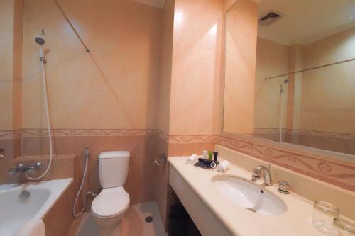 a bathroom with a toilet and a sink and a mirror at Kristal Hotel Kupang in Kupang