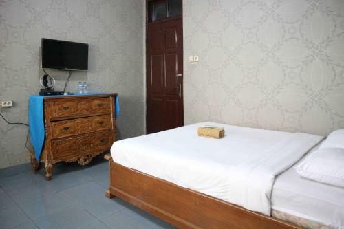 a bedroom with a bed and a dresser with a bag on it at Monjali Inn RedPartner near Tugu Yogyakarta in Jetis