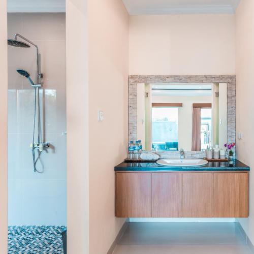a bathroom with a sink and a mirror at Kubu Petitenget Suite Seminyak in Seminyak